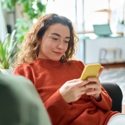 Woman looking at a smart phone while sitting on a lounge.